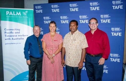 four people stand in front of CDU TAFE logo